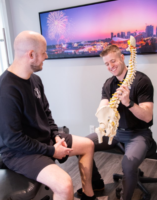 MYo Lab employee showing a model of a spine to a patient