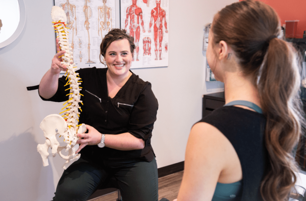 MYO Lab worker showing spine model to a patient