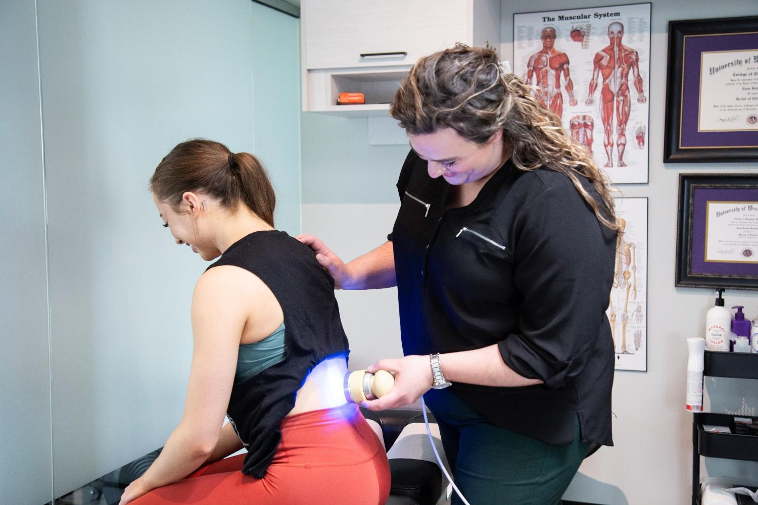 A MYo lab, therapist applying low-level laser therapy to a patient’s lower back.