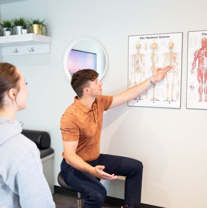 Chiropractor explaining spinal anatomy during a clinical assessment at MYo Lab Health & Wellness in Calgary.