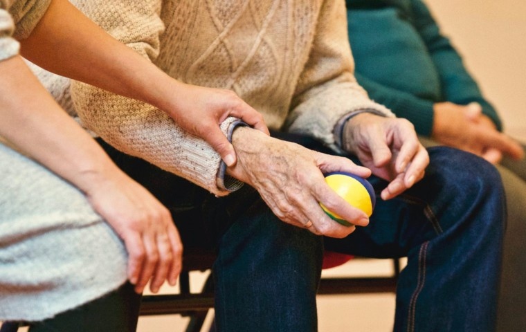 Hands assisting an older adult holding an exercise ball, representing gentle Chiropractic care, improved mobility, and joint support for seniors.
