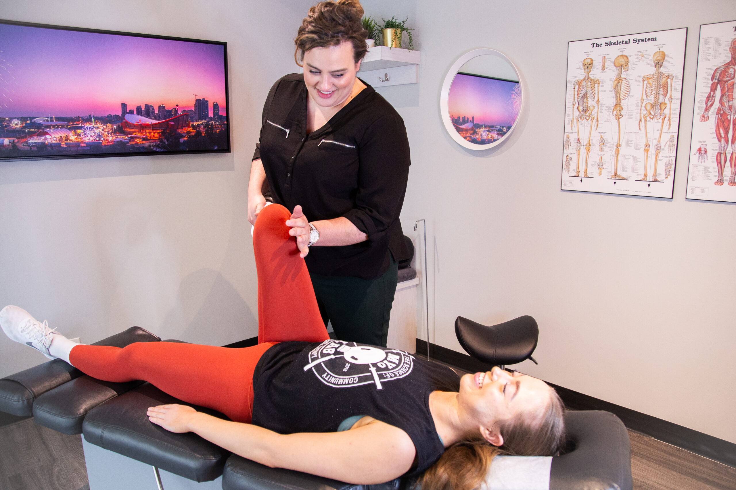 Chiropractor assisting a member with hip pain treatment using guided leg movement to improve joint mobility and reduce discomfort.