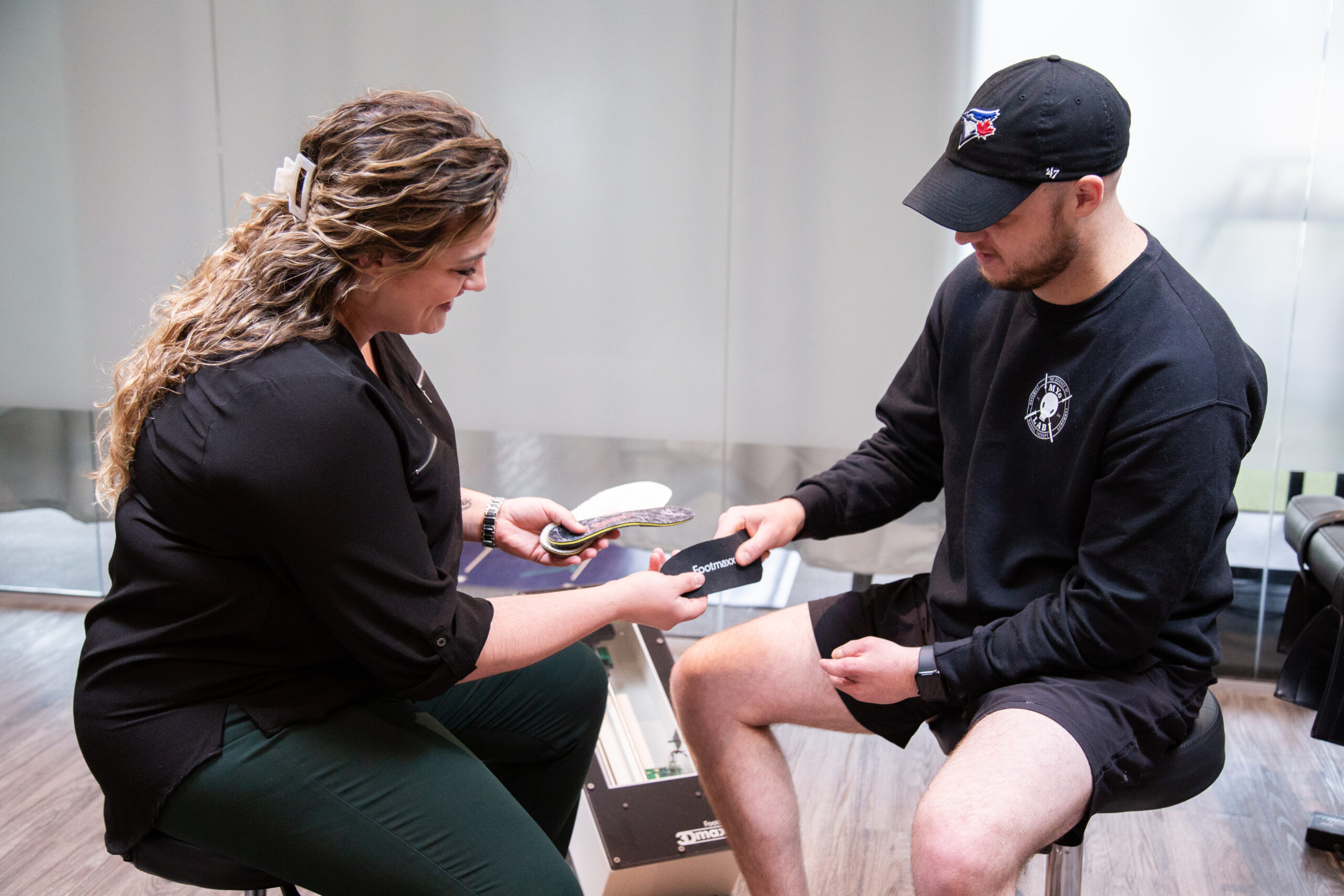 Clinician fitting custom orthotics during a personalized foot assessment at MYo Lab Health & Wellness in Calgary.