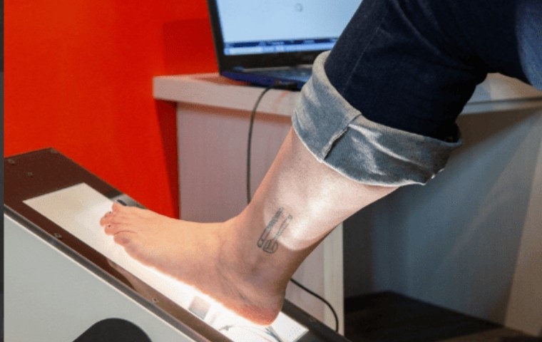 Member undergoing a digital foot scan for custom orthotics at MYo Lab Health & Wellness to assess foot alignment and pressure distribution.
