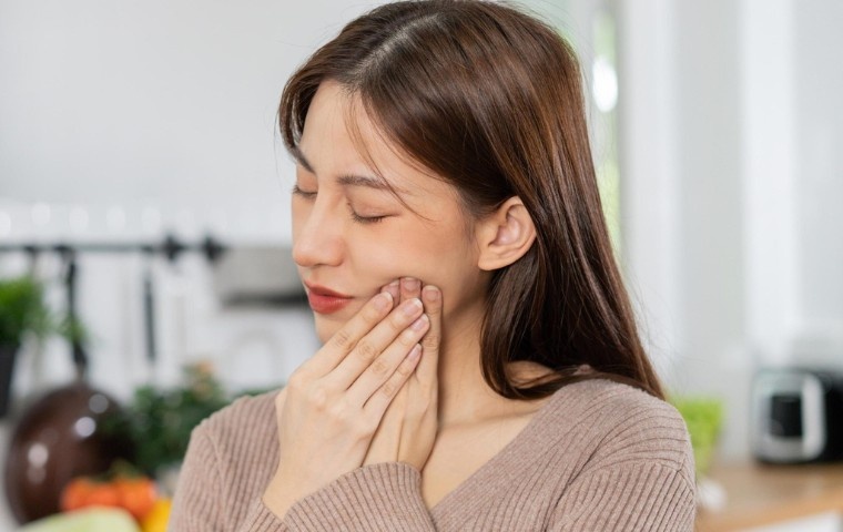 Person experiencing jaw pain and facial tension, common symptoms of TMJ and temporomandibular joint dysfunction.