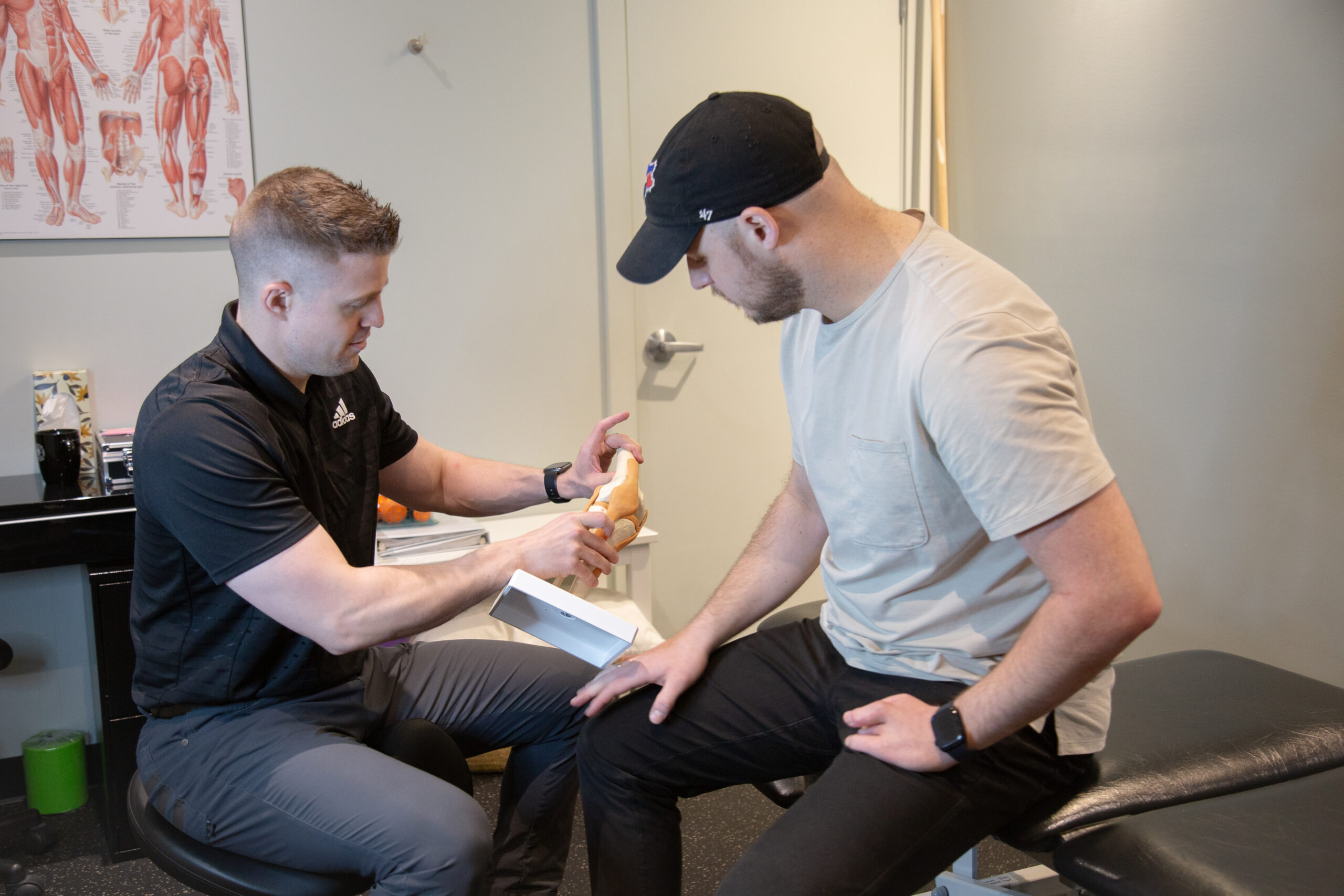 Clinician explaining knee pain and treatment options to a member using an anatomical knee model.