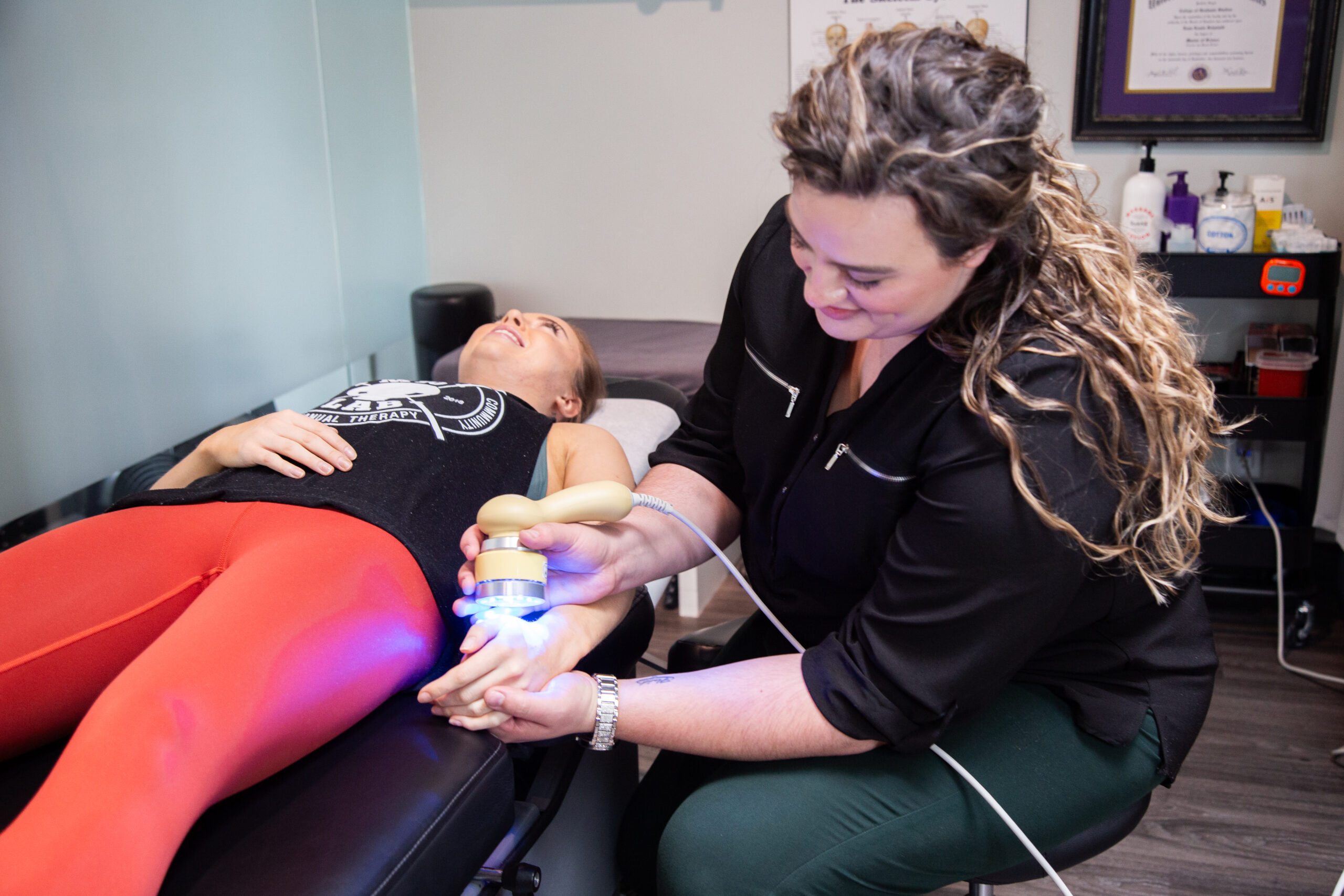 Physiotherapist providing low-level laser therapy to the elbow and wrist for pain relief at MYo Lab Health & Wellness in Calgary.