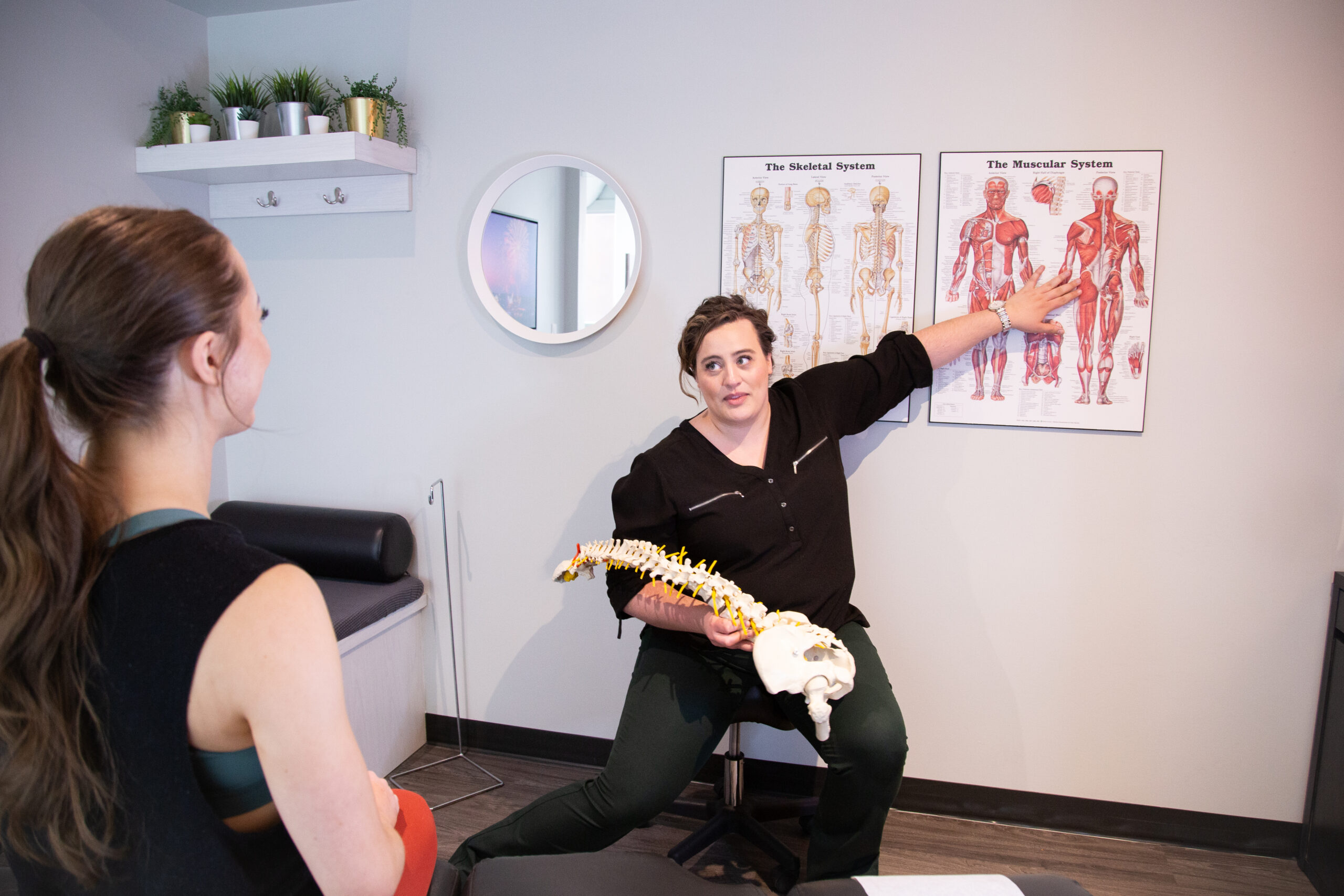 Clinician explaining posture problems using a spine model during a posture assessment focused on spinal alignment and movement mechanics.