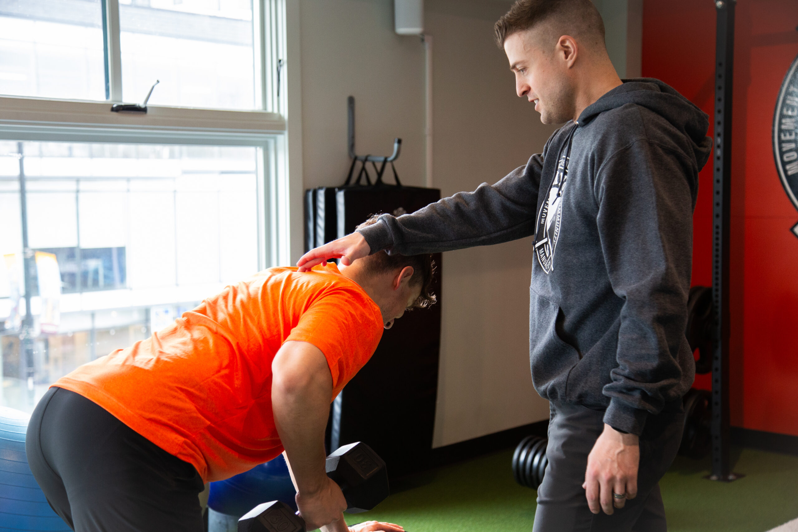 Therapist guiding strength training during sports injury rehabilitation to improve movement and prevent reinjury.