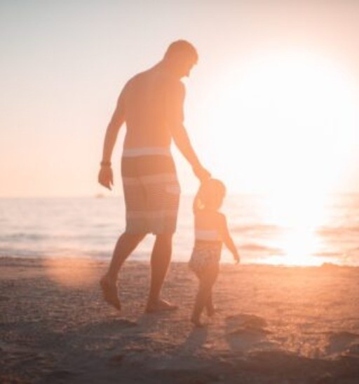 Parent walking with a young child on the beach, representing family wellness, healthy development, and preventative Chiropractic care for kids.