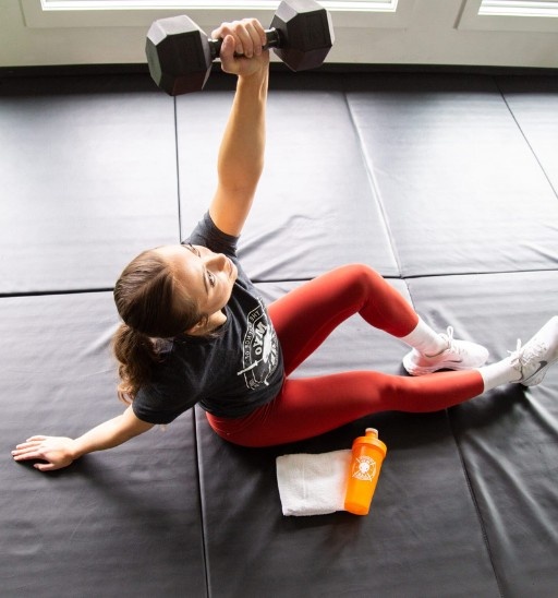 Client performs core stability dumbbell floor exercise on mat at MYo Lab Calgary.