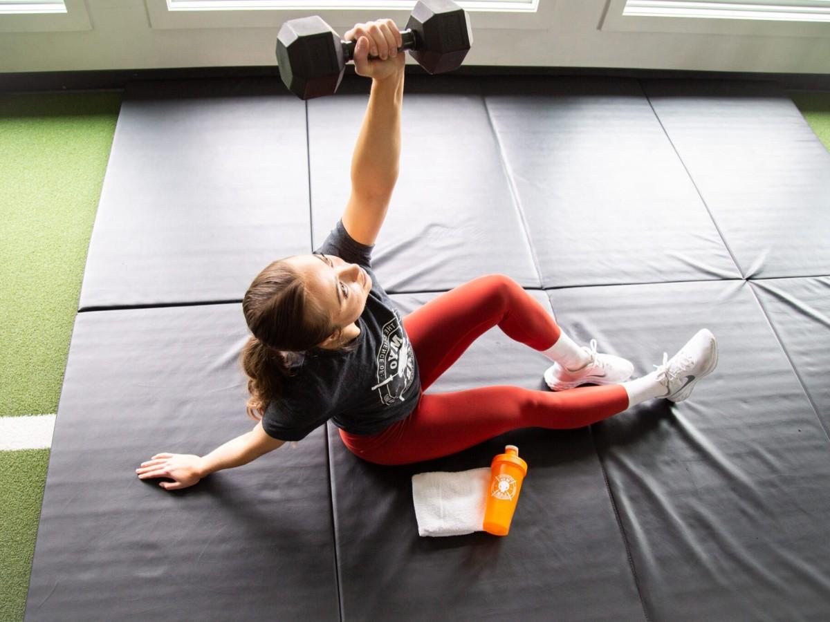 Client performs core stability dumbbell floor exercise on mat at MYo Lab Calgary.