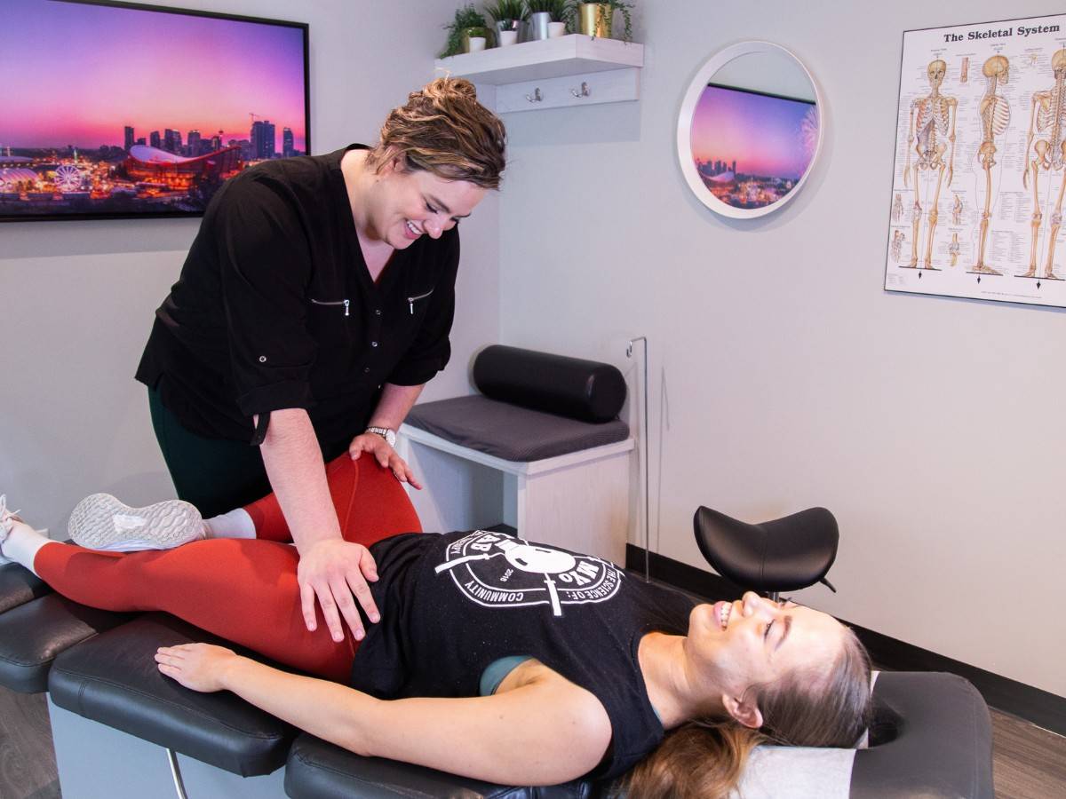 Chiropractor performing a hip and pelvic assessment at MYo Lab Calgary to evaluate stability and pain patterns related to hypermobility.