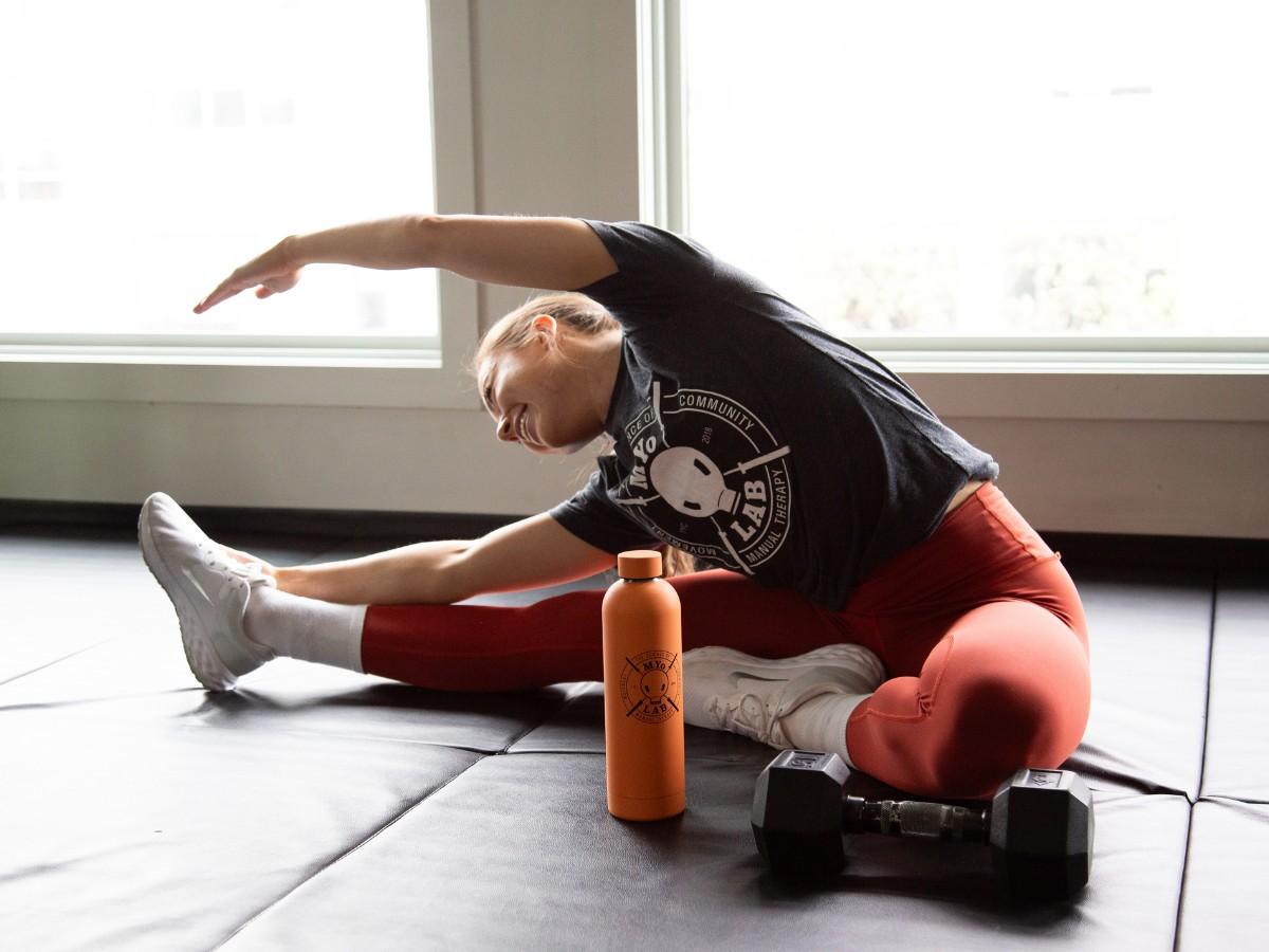 Woman performing a seated side stretch at MYo Lab Calgary, highlighting the difference between flexibility and stability training for hypermobility.