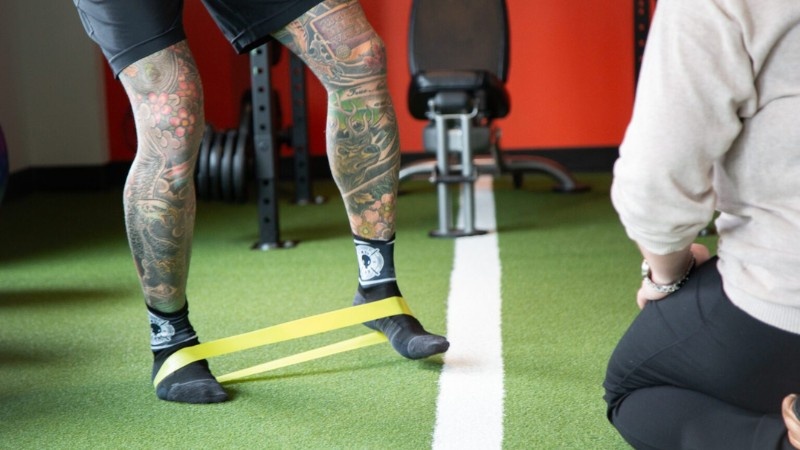 Patient performing a resistance band exercise during guided rehabilitation for chronic pain and improved movement capacity.