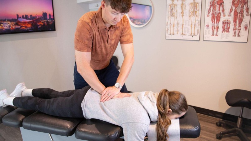 Clinician treating a patient’s lower back during an assessment for desk-related pain, stiffness, and reduced mobility.