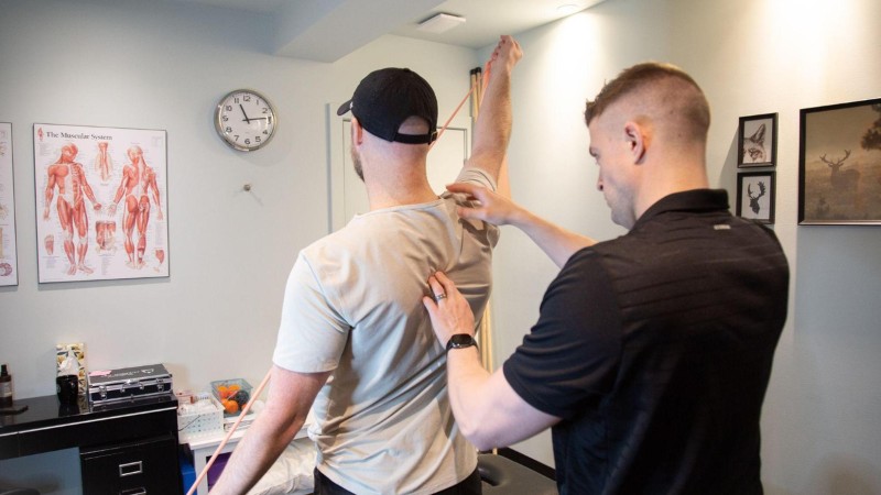 Clinician assessing shoulder mobility and movement before dry needling treatment for muscle tightness and trigger points.