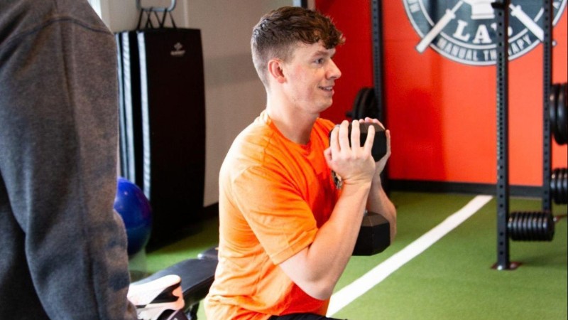Patient performing a controlled dumbbell exercise during rehabilitation to build strength, stability, and movement control.
